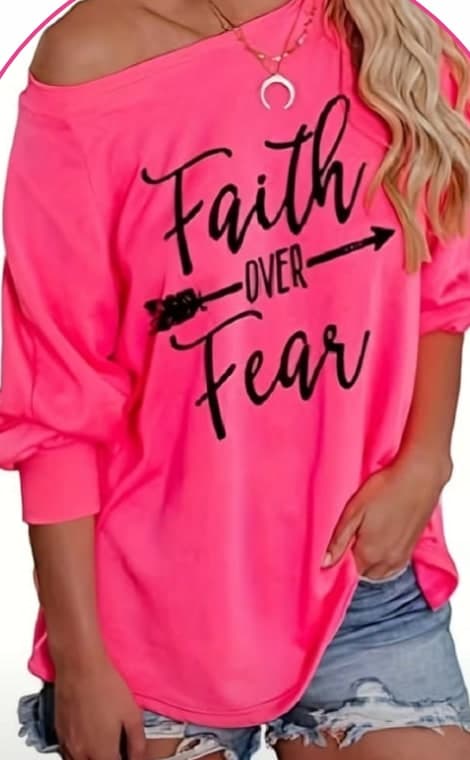 Model wearing a pink off-shoulder sweatshirt printed with the words Faith Over Fear