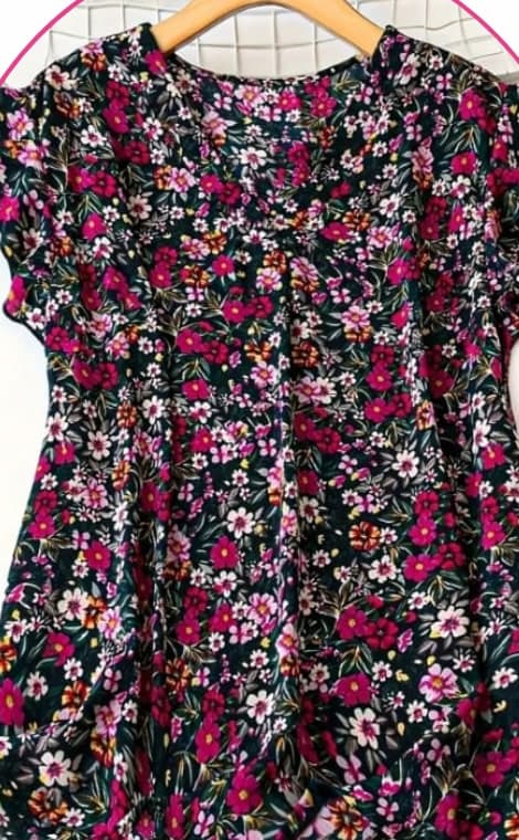 Navy blouse with a pink floral print and ruffle sleeves on a hanger